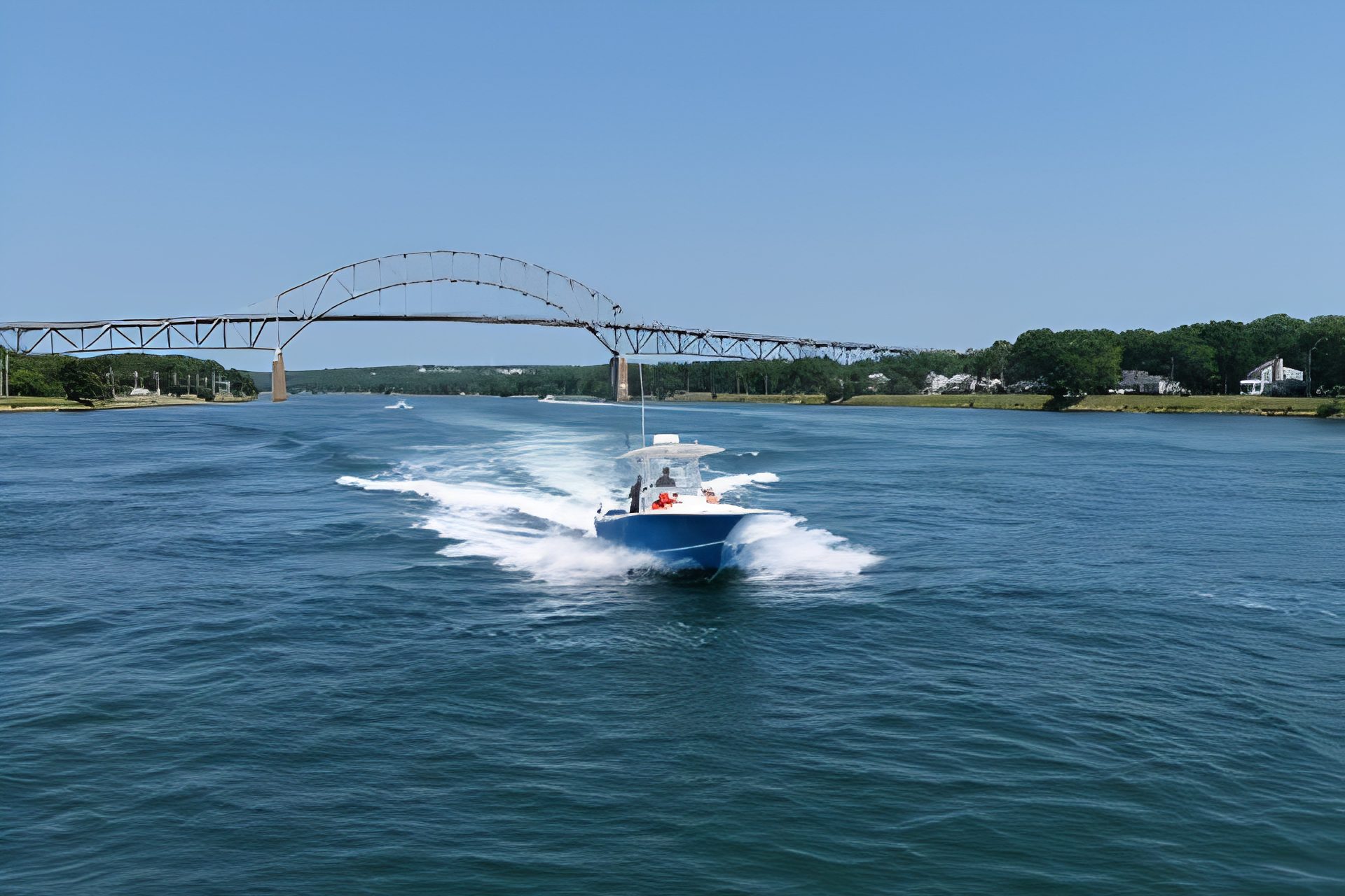 Boat speeding under an arched bridge.