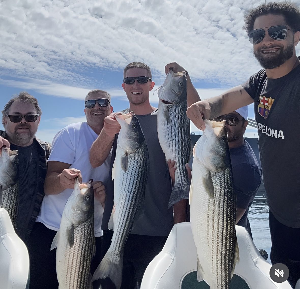 Group of men holding freshly caught fish.