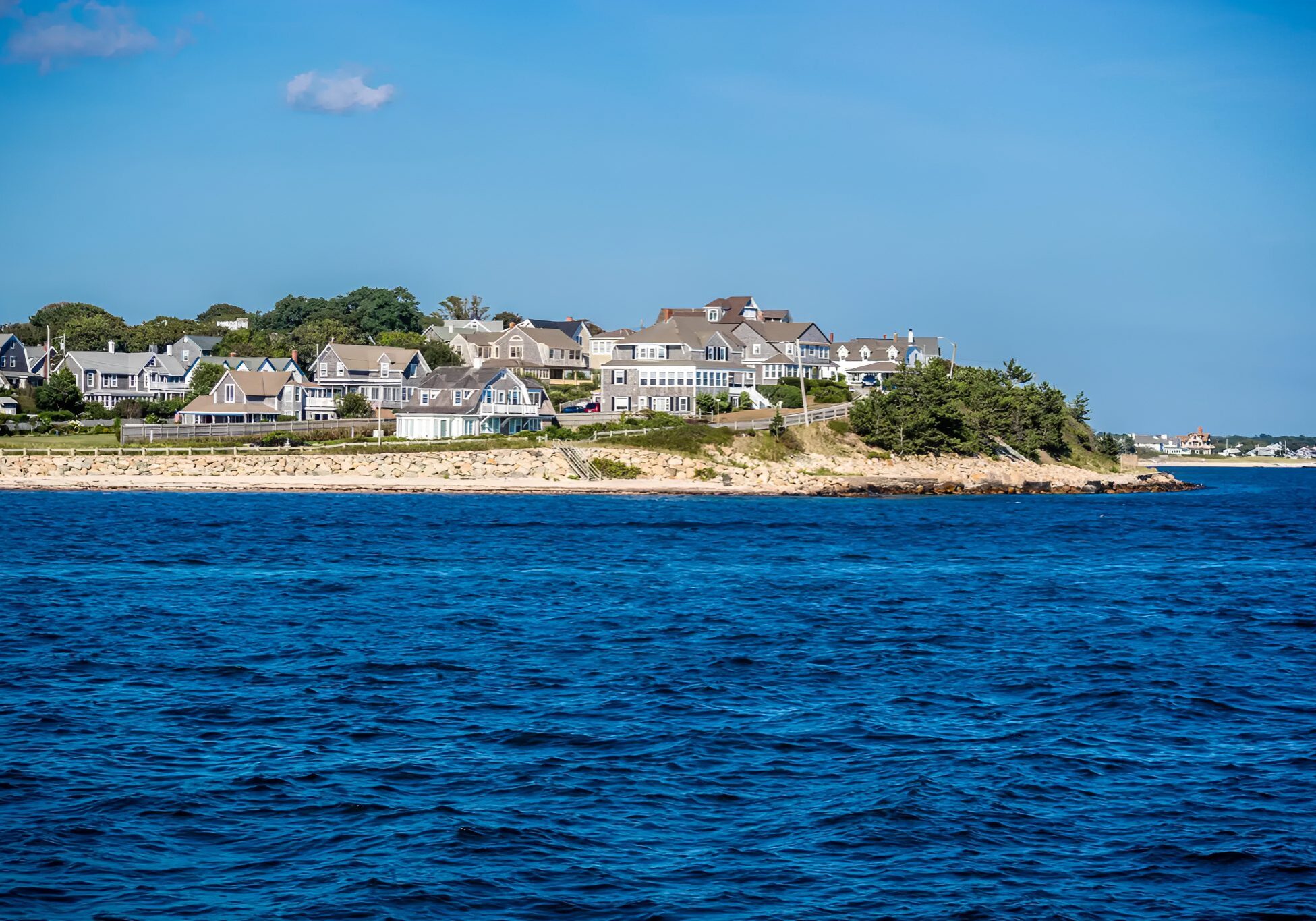 Coastal houses overlooking the ocean under blue sky.